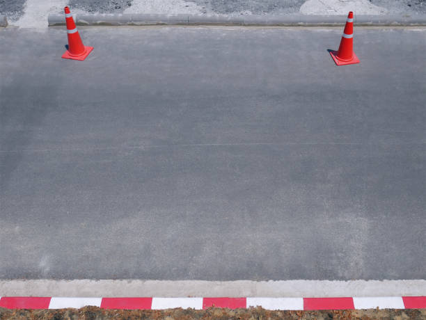 istock Orange Plastic Traffic Cones on Asphalt Road Opposite to Red White Stripes 1146909008