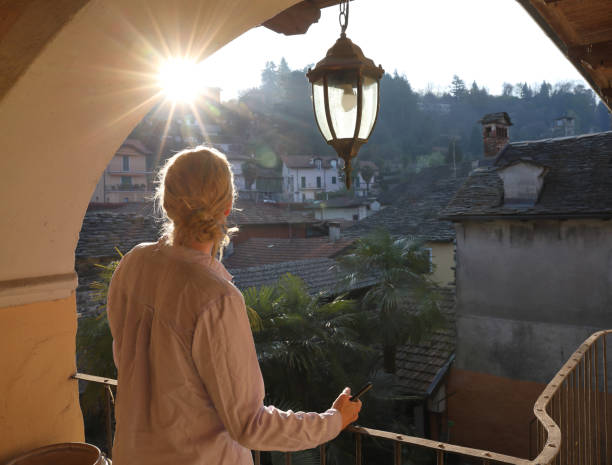 woman relaxes on balcony at sunset - women rear view one person arch imagens e fotografias de stock