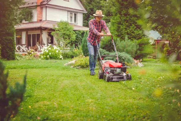 Photo of Man using a lawn mower in his back yard