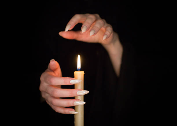 istock Candle and female witch hands with sharp pearl nails. Divination and witchcraft, low key. 1146913325