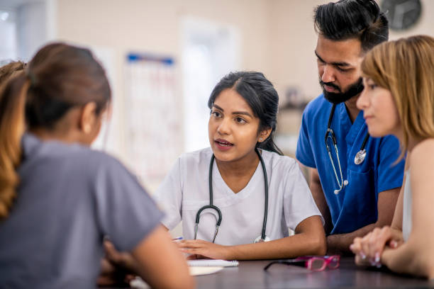 Doctor collaboration A multi-ethnic group of doctors are indoors in an office. They are gathered around a table for a meeting. One woman of Indian descent is taking notes. team event stock pictures, royalty-free photos & images