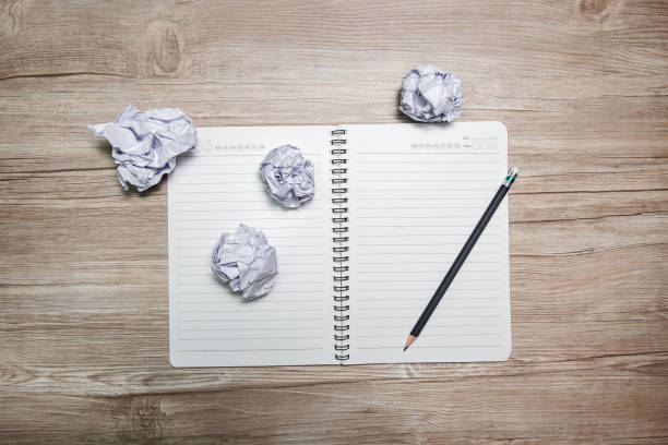 istock Crumpled paper ball and notebook on a black background. 1146918596