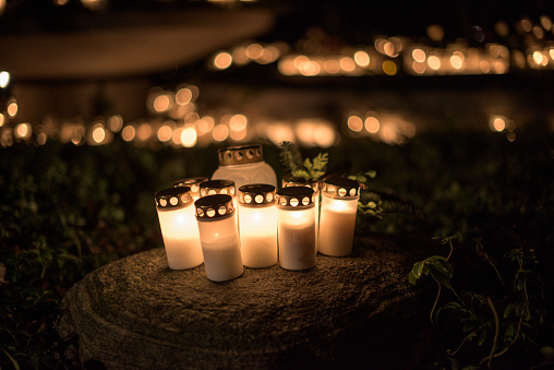 lit candles on a stone at a graveyard