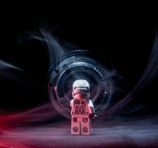 istock Toy figure looking into a metallic round object. Smoke and red light. 1146921392