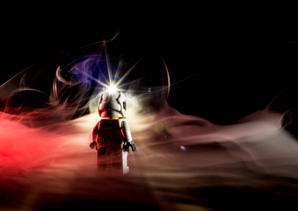 Toy figure looking into a dark object. Smoke and red light.