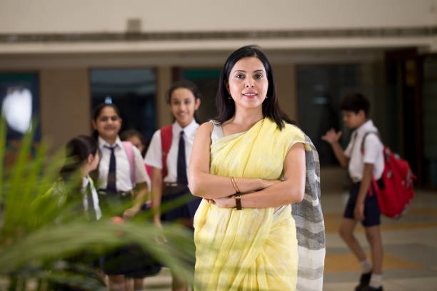 Confident female teacher with schoolboys and schoolgirls in campus