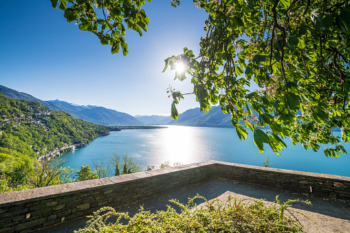 View from the village Ronco sopra Ascona at the Swiss part of the beautiful lake Lago Maggiore to the sunrise in the east. There is a big chestnut tree and an idyllic patio.