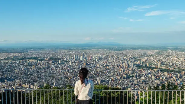 Young woman is looking Sapporo City from the Mount Moiwa, Hokkaido, Japan.