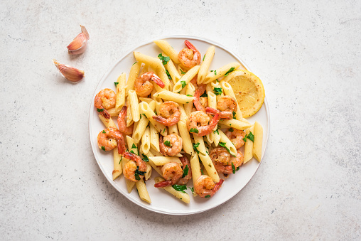 Penne Pasta with Prawns or Shrimps, lemon and garlic on white, top view, copy space. Lemon pasta with sauteed shrimps, fresh seafood.
