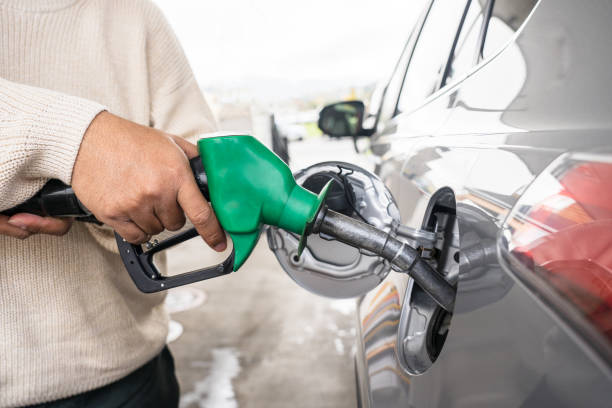 remettez la voiture avec du carburant à la station de ravitaillement. voiture grise à la station d’essence étant remplie de carburant en nouvelle-zélande. manipuler la buse de carburant pour faire le plein. installation de ravitaillement des véhicul - gasohol photos et images de collection