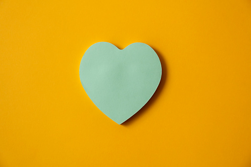 Blue paper heart stick note on a yellow background