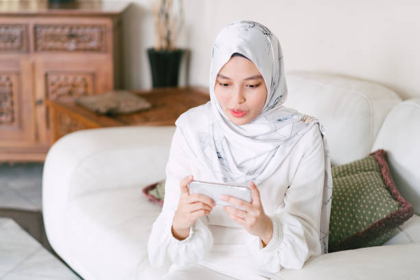 istock Young Muslim Woman Playing Mobile Phone Game 1146945111