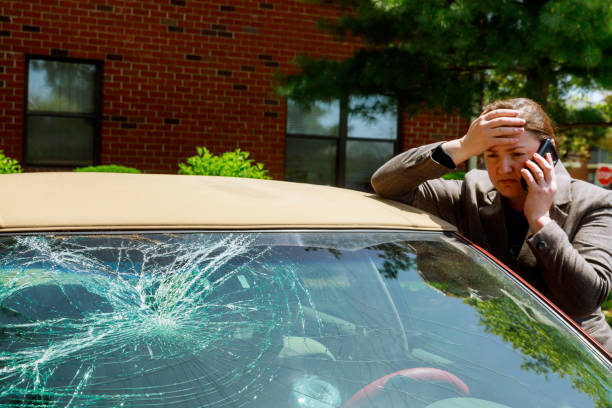 mulher que faz um atendimento de telefone ao lado do carro danificado após um acidente de carro - broken window glass women - fotografias e filmes do acervo