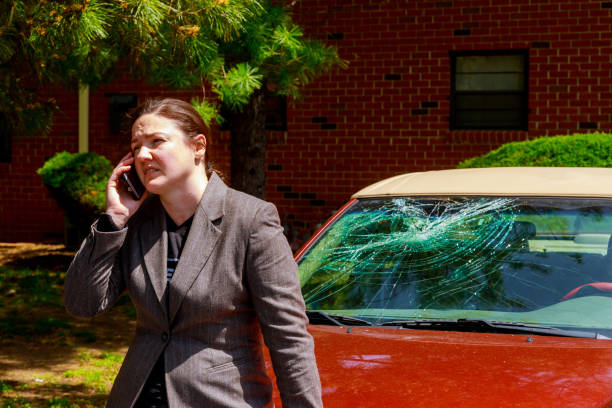 mujer haciendo una llamada telefónica por el parabrisas dañado después de un accidente de coche - broken window glass women fotografías e imágenes de stock