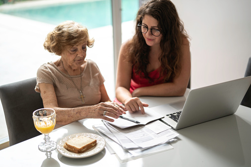 Granddaughter helping grandmother, using laptop