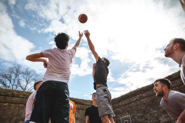 молодые друзья играют в баскетбол вместе на открытом воздухе - basketball sport human hand reaching стоковые фото и изображения