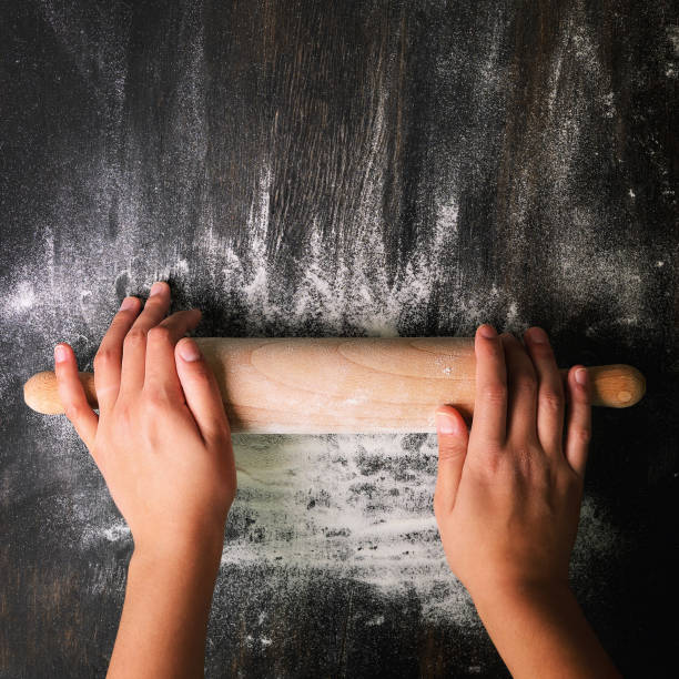 istock Girl hands keep rolling pin with flour on dark black table, baking background, top view, copy space for your text, meru, recipe. Square crop. 1146957530
