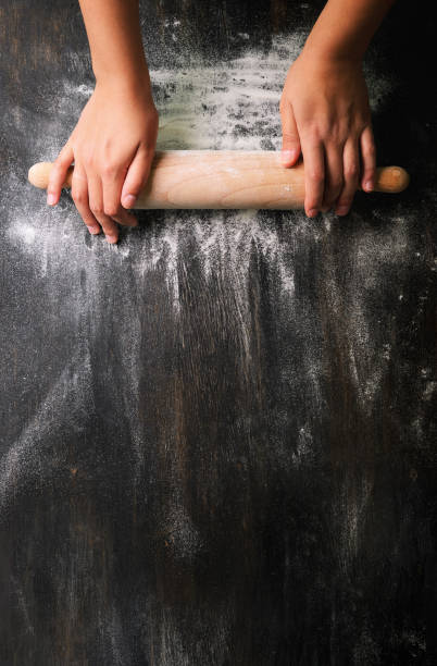 소녀 손은 어두운 검은 색 테이블, 베이킹 배경, 상단 보기, 텍스트, 메루, 조리법에 대 한 복사 공간에 밀가루와 함께 롤링 핀을 유지 합니다. 배너 - flour dough cooking food 뉴스 사진 이미지
