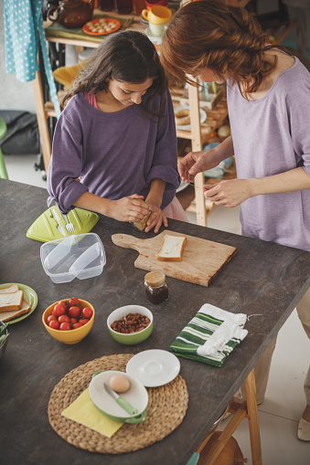 High angle view of a woman and her daughter preparing healthy lunch at the kitchen table.