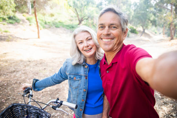 senior couple riding bicycles in nature - action mature adult bicycle senior couple imagens e fotografias de stock