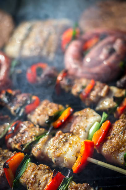 Close up pf delicious chicken breast on wooden skew with fresh vegetables, garlic, paprika fried on mangal barbeque grill and smoke