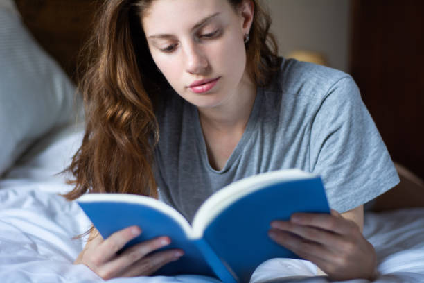 istock woman laying in bed and reading book 1146962815