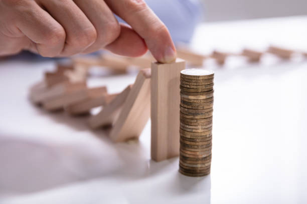 istock Human Hand Stopping Wooden Blocks From Falling On Stacked Coins 1146964366