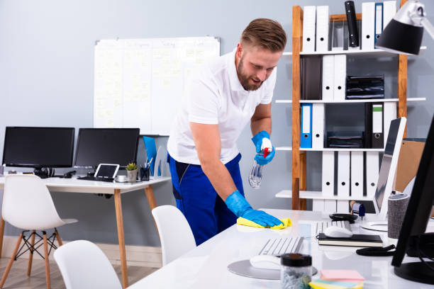 istock Janitor cleaning white desk in office 1146964983