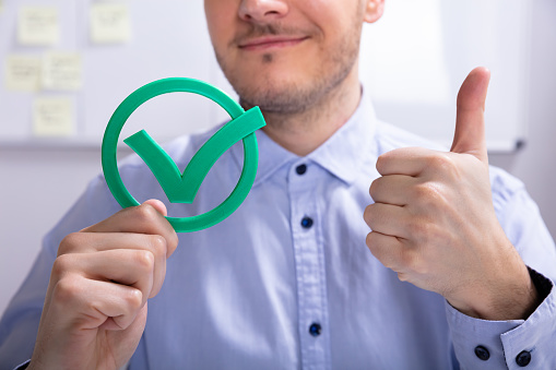 Smiling Young Businessman Showing Thumbs Up Sign With Green Check Mark Icon