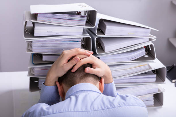 istock Stressed Businessman In Front Of Stacked Folders 1146965337