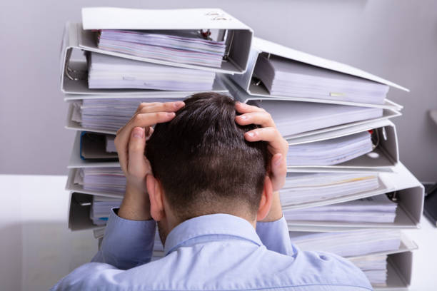 istock Stressed Businessman In Front Of Stacked Folders 1146965342