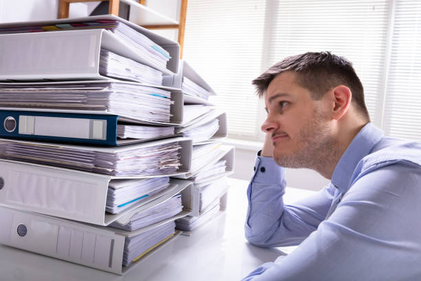 istock Stressed Businessman In Front Of Stacked Folders 1146965345