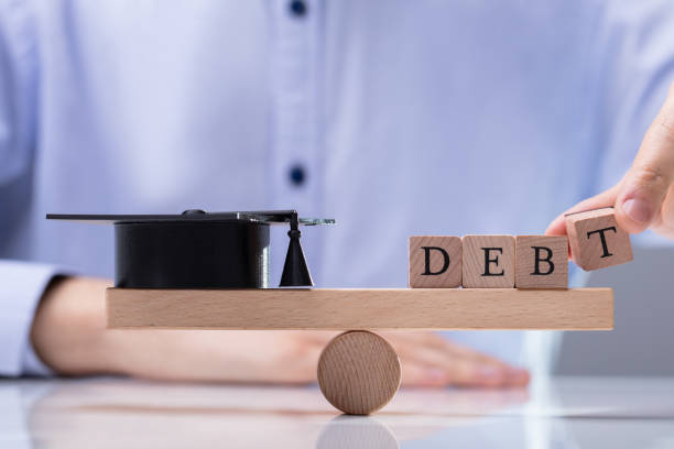 istock Debt Word And Graduation Hat Balancing On Seesaw 1146965414