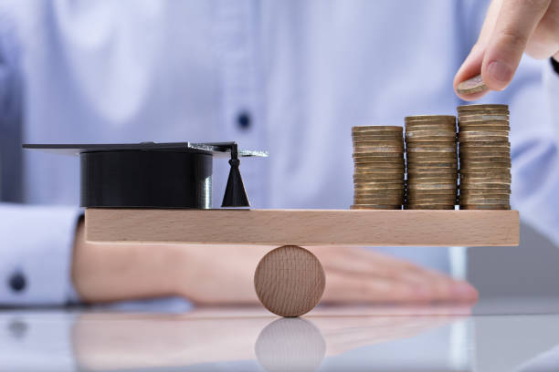 istock Graduation Hat And Stack Of Coins On Seesaw 1146965429