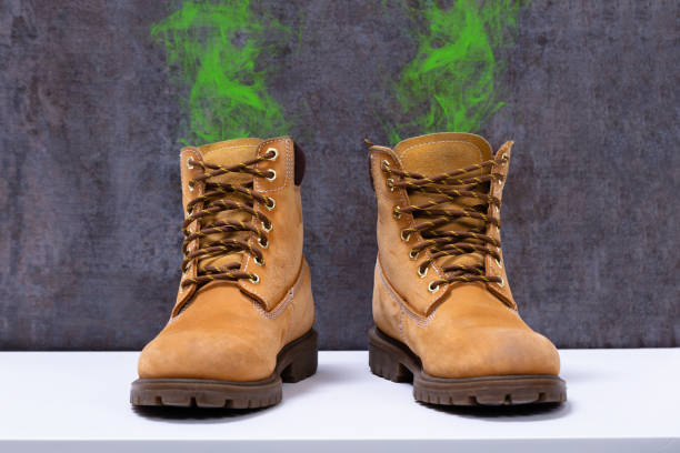 Pair Of Dirty Boots With An Unpleasant Smell Kept Over White Desk