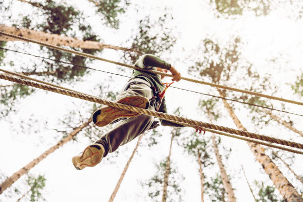 child doing an obstacle course high above the ground, walking on a rope, balancing not to fall