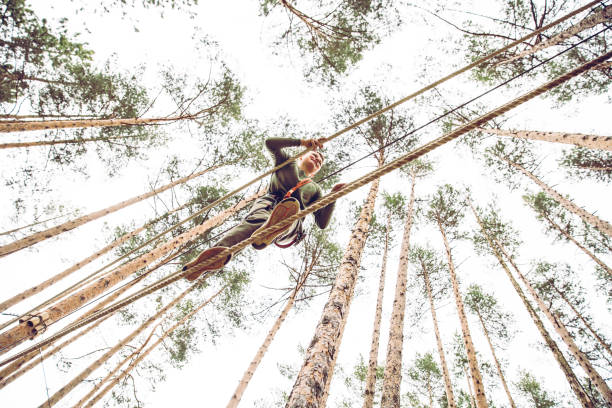 equilibrage sur un cours de corde au parc d’aventures - high up obstacle course ropes course teenage boys photos et images de collection