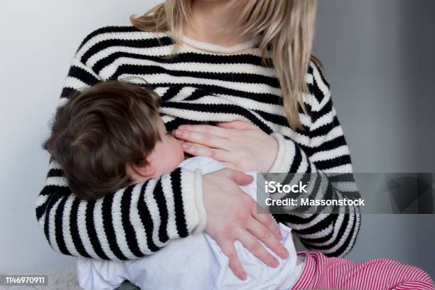 Young Mother Breastfeeding Toddler Boy In Striped Sweater Stock Photo - Download Image Now