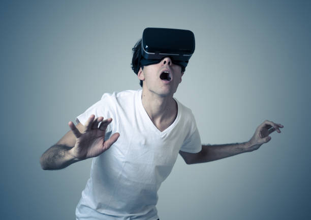 istock VR experience. Amazed and excited man using 360 VR headset goggles, feeling excited about simulation, making gestures having fun interacting with new virtual world. In Innovation and new technology. 1146973020
