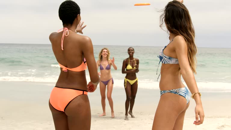 Group of mixed-race female friends playing flying disc on the beach 4k