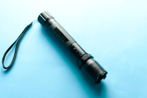 istock A black metal flashlight with shocker at the blue background. protection and security concept. for design and decoration. 1146974447