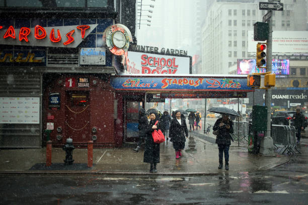 New York City, NY - March 10, 2017: Unidentified Chinese woman waiting under the snow and for the street light to change in Broadway avenue in Manhattan, NY