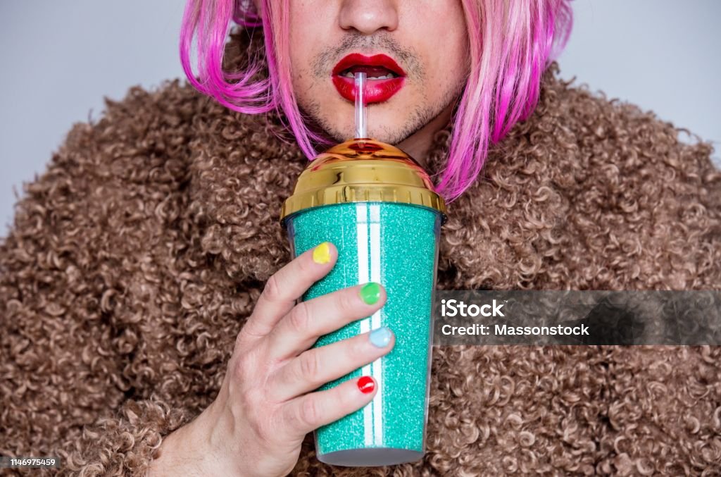 transvestite man with lipstick and polish nail holding cocktail Cross Dressing Stock Photo