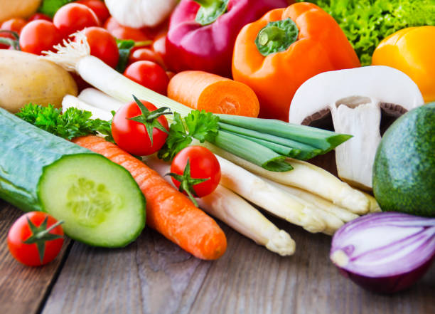 istock Various vegetables and herbs against wooden background 1146980663