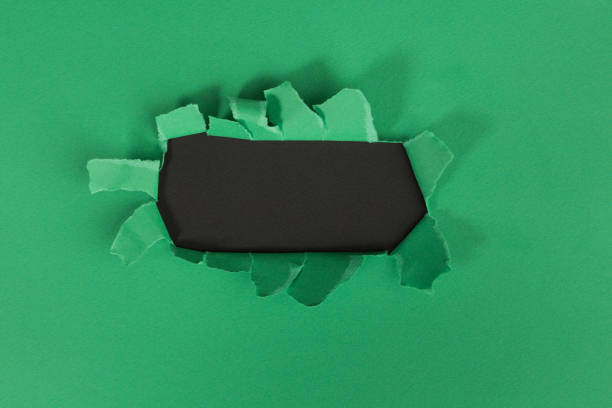 istock ragged Hole torn in ripped paper on green background 1146981444