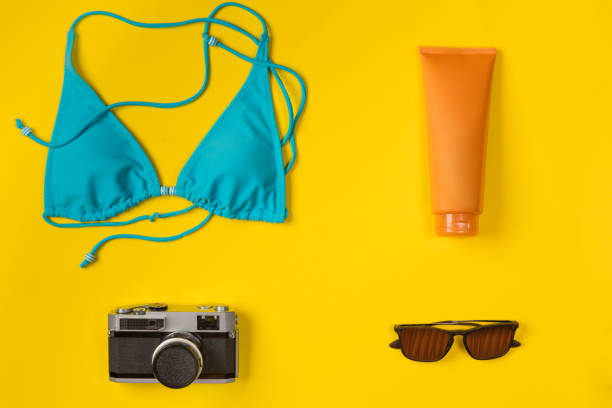 istock swimsuit, sunscreen, camera, sunglasses on a yellow background, top view 1146981460