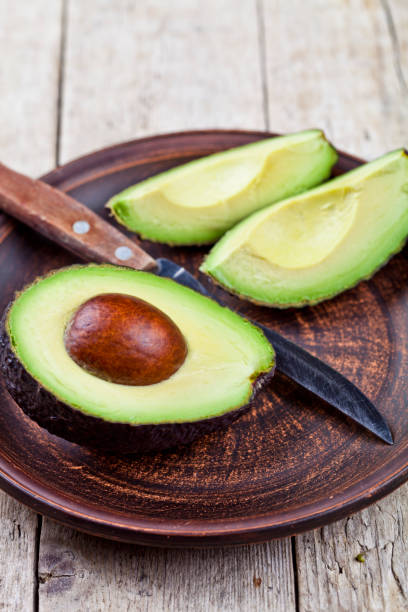 istock Fresh organic avocado on ceramic plate and knife on rustic wooden table background. 1146984033