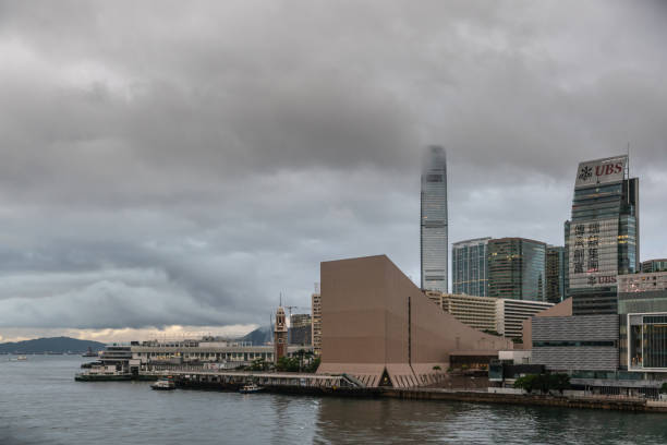 Hong Kong Cultural Center early morning, Hong Kong China. Hong Kong, China - March 7, 2019: Very early morning under dark rainy sky. Kowloon skyline with Hong Kong Cultural Center up front. ICC tower in back. international commerce center stock pictures, royalty-free photos & images