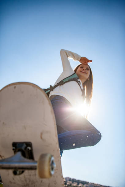 istock Smiling Girl Riding Skateboard Outdoors From Low Angle View 1146994538