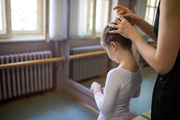 Mother fixing her daughters hair for an upcoming ballet class